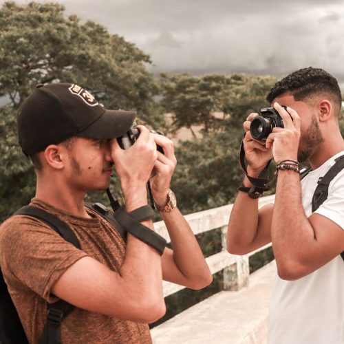 Fotografia de dois jovens se fotografando com câmera.